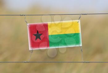 Border fence - Old plastic sign with a flag - Guinea Bissau
