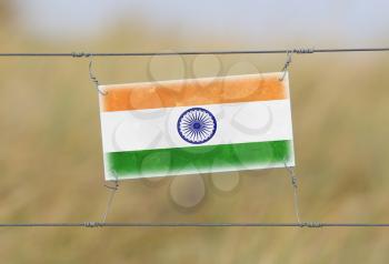 Border fence - Old plastic sign with a flag - India