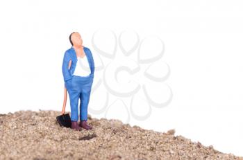 Miniature worker with a shovel on a mountain of sand