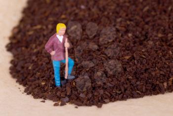 Miniature worker with pickaxe working on grinded coffee