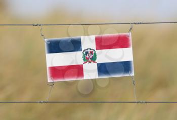 Border fence - Old plastic sign with a flag - Dominican Republic