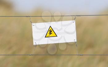 Border fence - Old plastic sign with a flag - Electic