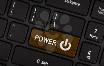 Close-up of a brown power button on a black laptop keyboard