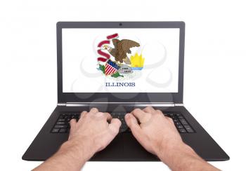 Hands working on laptop showing on the screen the flag of Illinois