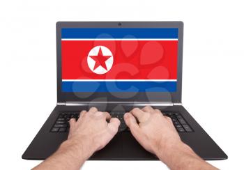 Hands working on laptop showing on the screen the flag of North Korea