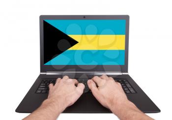 Hands working on laptop showing on the screen the flag of Bahamas