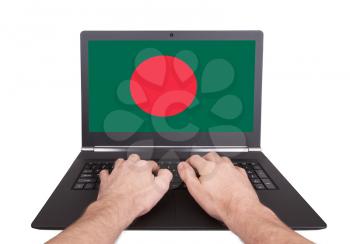 Hands working on laptop showing on the screen the flag of Bangladesh