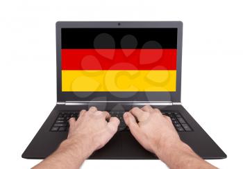 Hands working on laptop showing on the screen the flag of Germany