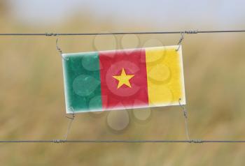 Border fence - Old plastic sign with a flag - Cameroon