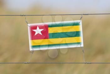 Border fence - Old plastic sign with a flag - Togo