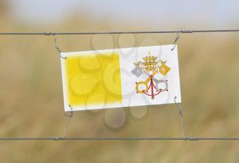 Border fence - Old plastic sign with a flag - Vatican City