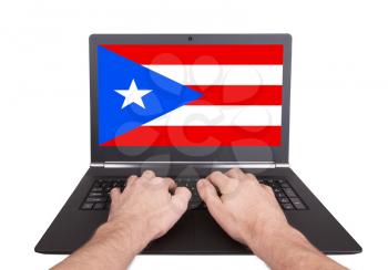 Hands working on laptop showing on the screen the flag of Puerto Rico