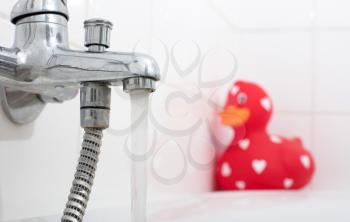 Large red rubber duck in a bathtub, selective focus