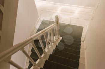 White wooden stairs with green carpet, going downstairs