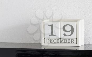 White block calendar present date 19 and month December on white wall background