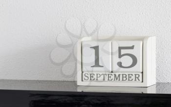 White block calendar present date 15 and month September on white wall background