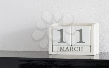 White block calendar present date 11 and month March on white wall background