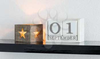 White block calendar present date 1 and month September on white wall background