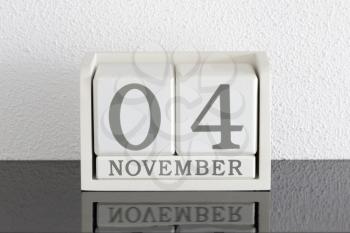 White block calendar present date 4 and month November on white wall background