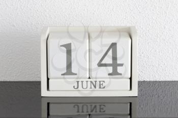 White block calendar present date 14 and month June on white wall background