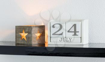 White block calendar present date 24 and month July on white wall background