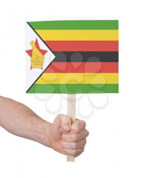 Hand holding small card, isolated on white - Flag of Zimbabwe