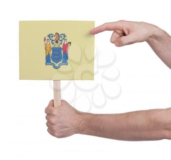 Hand holding small card, isolated on white - Flag of New Jersey