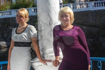 Two beautiful smiling girls standing near the column