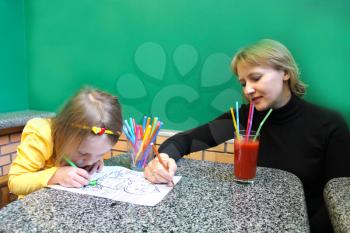 little girl and her mother draw the drawing at the table