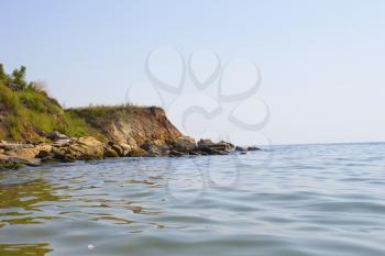 Sea shore with forest under sky. Beautiful landscape with trees on cliff and sea. View from the sea