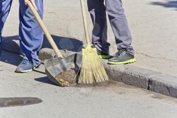 Photo of two men legs cleaning street with broom and shovel