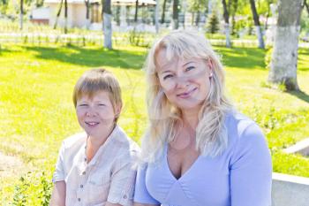 Happy blond woman and son smiling in the summer park