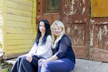 Two women are sitting on wooden porch
