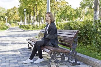 Beautiful girl fourteen years old are sitting on the bench