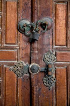 Old brown wooden door with old door handle closed under padlock