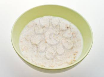 traditional english oat porridge with milk in ceramic bowl on white table