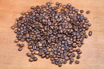 handful of roasted coffee beans on wood plank close up