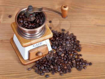 heap of coffee and vintage manual coffee mill with beans on wooden table