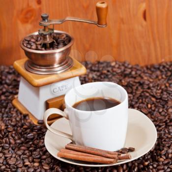 cup of coffee and roasted coffee beans with retro manual mill, cinnamon