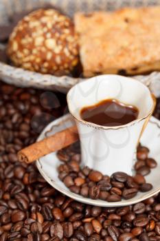 above view small cup of coffee and roasted coffee beans with cinnamon, biscuit close up