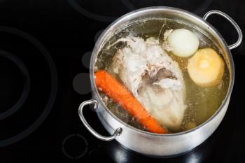 boiling of chicken broth in steel pan on glass ceramic cooker