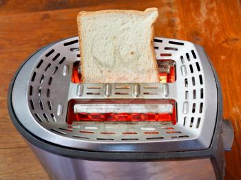 one fresh slice of bread on hot metal toaster on wooden table