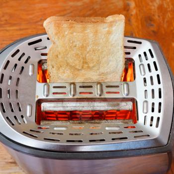 prepared toast on hot metal toaster at wooden table