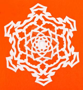 hand made cut out white snowflake on orange paper