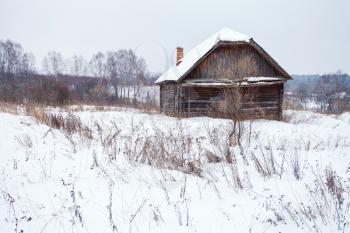 abandoned rustic house in snow-covered village in winter day