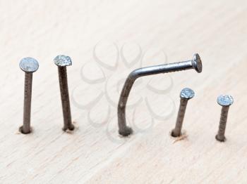 line of nails and curved nail in wooden board