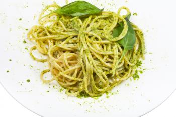 spaghetti mixed with pesto and basil leaf on plate isolated on white background