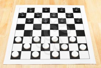 Starting position on vinyl 8x8 checkers board on wooden table