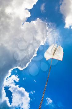 book tied on chain soars into dark blue sky