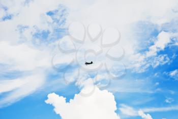 summer cloudscape with white clouds and small green airplane in blue sky